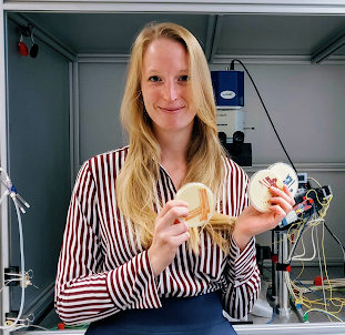 Female scientist standing holding chocolate petri dishes.